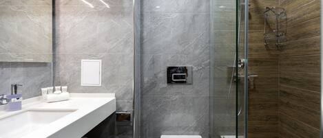 A modern bathroom with a marble vanity, a glass shower enclosure, and a wooden accent wall.