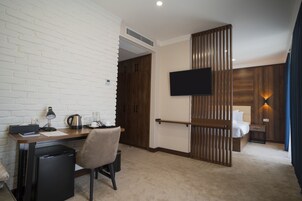 Una habitación de hotel con escritorio, silla y cama con televisor montado en la pared.