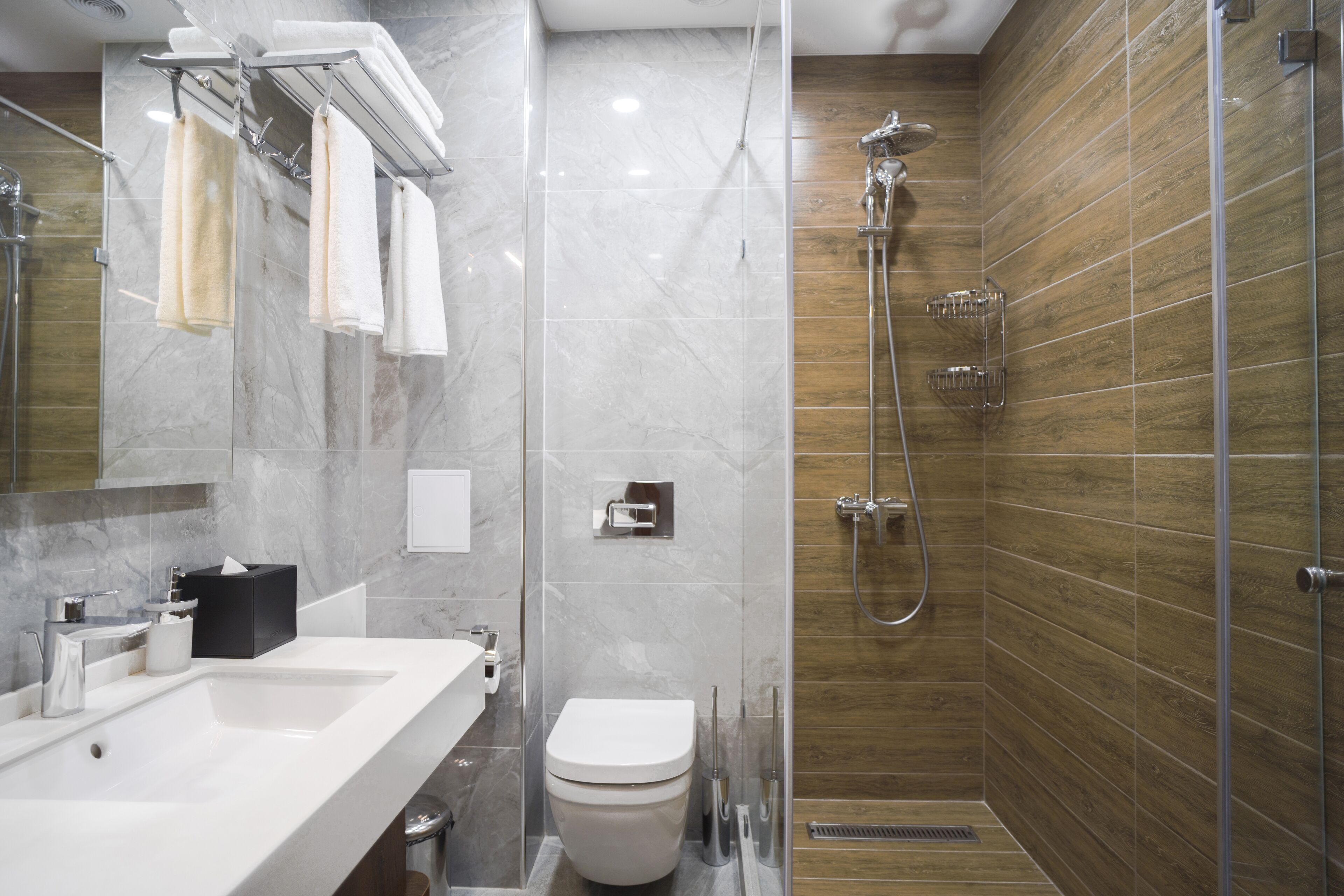Un baño moderno con tocador de mármol, inodoro y zona de ducha con mampara de vidrio.