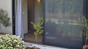 A sliding glass door leading to a room with a view of a wooden fence and greenery.
