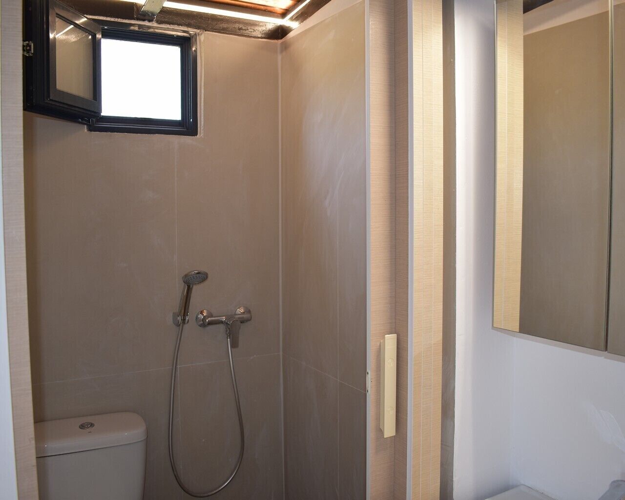 Ein kleines, separates Badezimmer mit Toilette, Dusche und Spiegel.