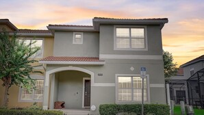 A two-story house with a grey facade, a tiled roof, and a small front porch. - Disney 10mins, Free heated Private Pool, Security Gated, Luxury stay in Orlando (Kissimmee)