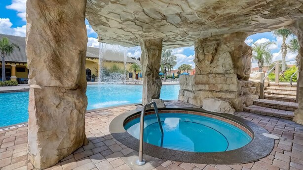 A hot tub under a stone arch with a pool in the background. - Disney 10mins, Free heated Private Pool, Security Gated, Luxury stay in Orlando (Kissimmee)