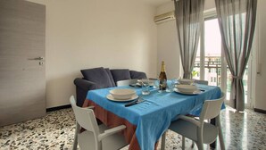 A dining area with a table set for four, a sofa, and a view of the outside. - Appartamento con A/c, Lavastoviglie e Ascensore (Imperia)