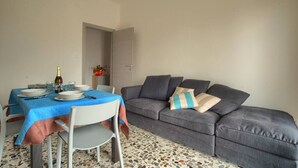 A dining area with a table set for four, a grey sofa, and a terrazzo floor. - Appartamento con A/c, Lavastoviglie e Ascensore (Imperia)
