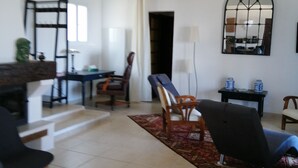 Amplia sala de estar con techo alto, una mesa de comedor, varias sillas, un espejo grande y una escalera que conduce a otro nivel.