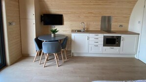 Une cuisine compacte avec un coin repas, un téléviseur à écran plat fixé au mur et un four à micro-ondes encastré.