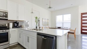 Una cocina moderna con armarios blancos, electrodomésticos de acero inoxidable y una isla central.