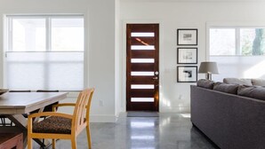 Una sala de estar moderna con un sofá, una mesa de comedor con sillas y una puerta de madera con listones horizontales.