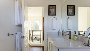 Un baño moderno con un espejo grande, un lavamanos y un perchero para toallas.