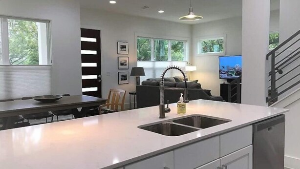 Cocina moderna con isla central, electrodomésticos integrados y zona de comedor con vistas al exterior.