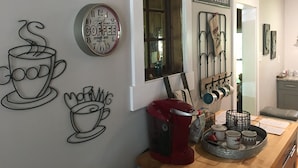 Een keuken met een koffiezetapparaat, een klok en wanddecoratie.