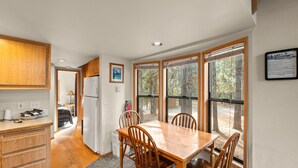 Una cocina con armarios de madera, un refrigerador y una zona de comedor con mesa y sillas.