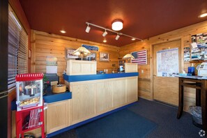 A wooden interior with a reception desk, a popcorn machine, and a map on the wall.