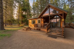 Una cabaña con terraza, mesa de picnic y señalización de zona de fogata.