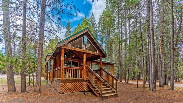 Une cabane avec une façade en bois, une véranda et un escalier menant à l’entrée.