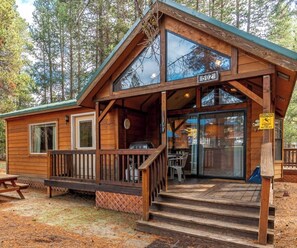 A wooden cabin with a porch, a picnic table, and a sign indicating the number 502.
