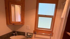 Une petite salle de bain en bois, avec un lavabo, des toilettes et une fenêtre.