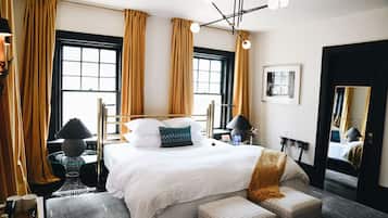 A hotel room with a large bed, two bedside tables, a mirror, and a window with curtains.