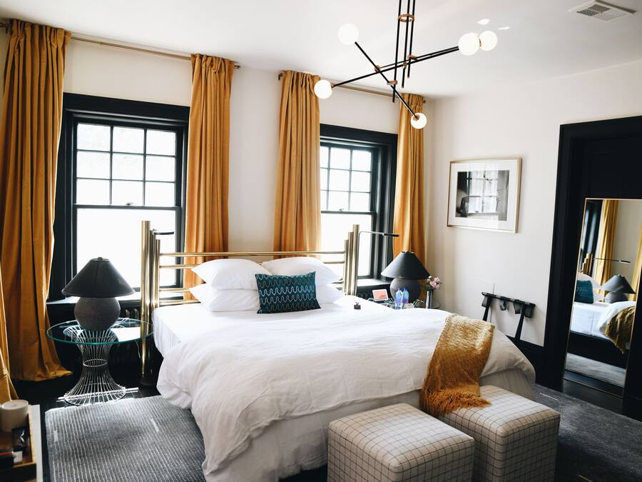 A hotel room with a large bed, two bedside tables, a mirror, and a window with curtains.