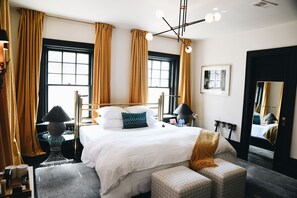 A hotel room with a large bed, two bedside tables, a mirror, and a window with curtains. - Truitt Hotel (Kansas City)