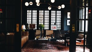 A cozy, dimly lit lounge area with a patterned rug, leather sofas, and a coffee table. - Truitt Hotel (Kansas City)
