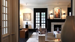 A modern living room with a fireplace, a sofa, a coffee table, and a glass table. - Truitt Hotel (Kansas City)