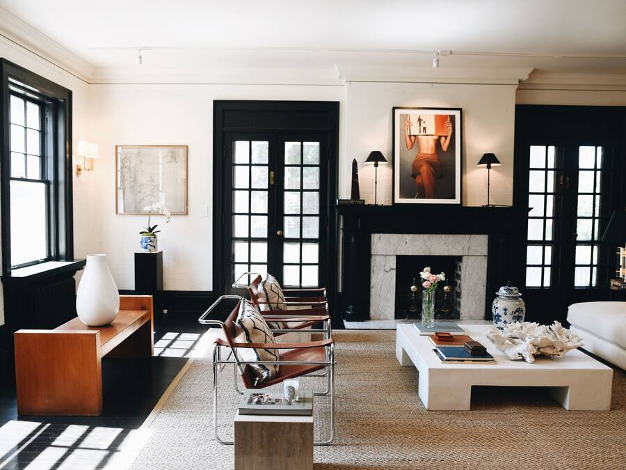 Una sala de estar moderna con chimenea, sillones de cuero, un sofá blanco y una mesa de centro con libros y objetos decorativos.