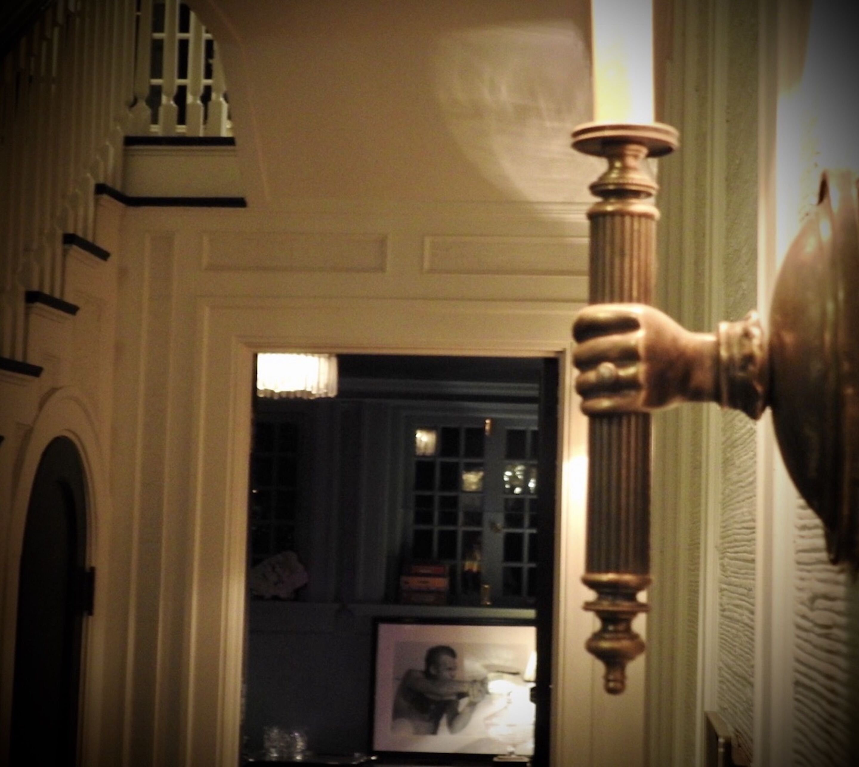 A grand hallway with a large, ornate column and a framed picture on the wall.