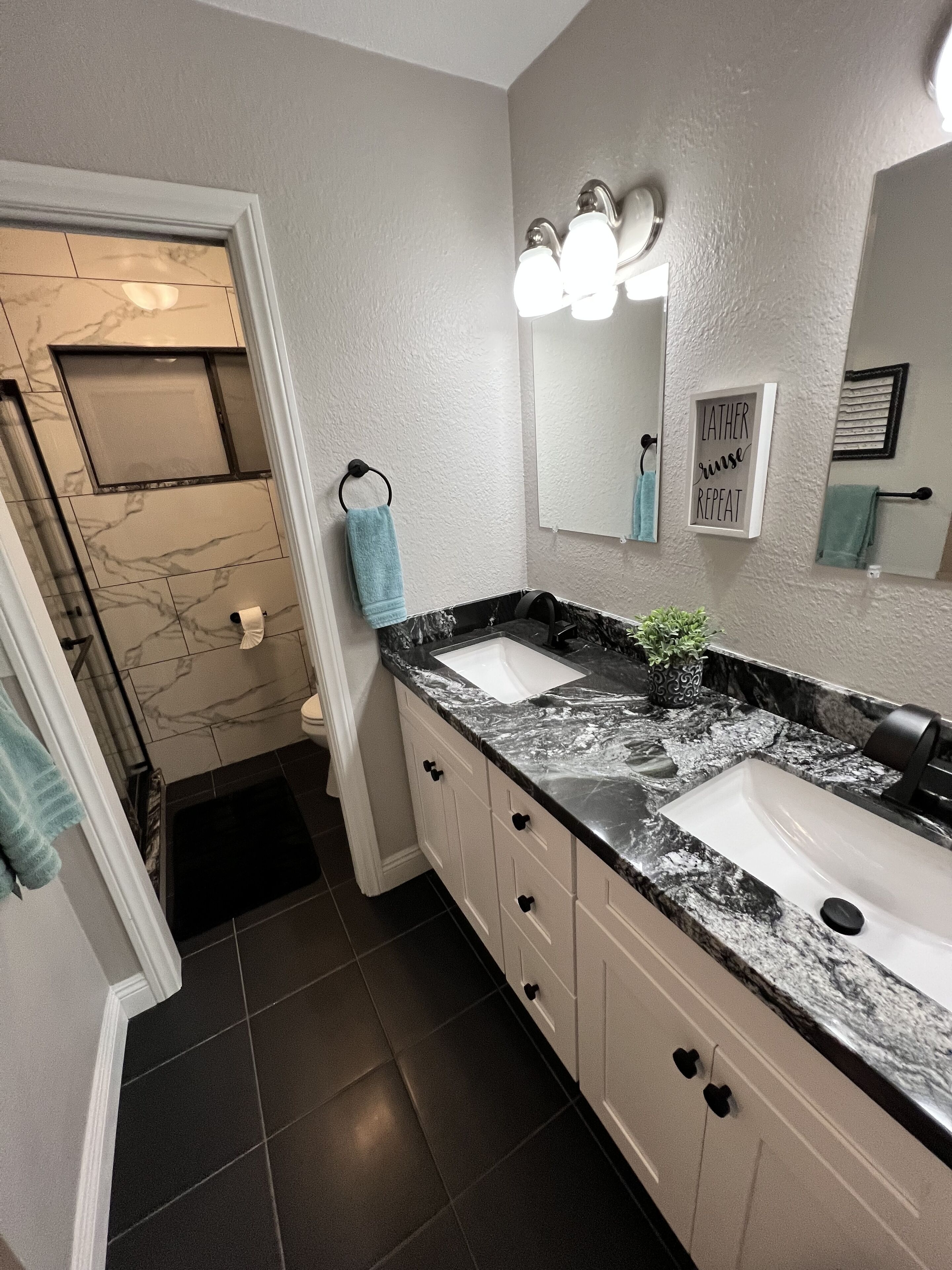 Une salle de bain moderne avec deux lavabos, un miroir et un porte-serviettes.