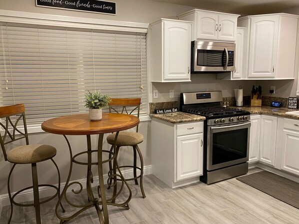 Modern kitchen with a gas stove, oven, microwave, and dining table for four.