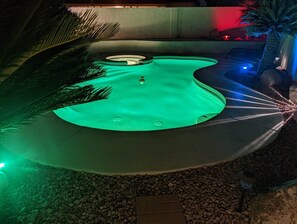 Relax by the unique, organically shaped pool surrounded by lush plants and a natural stone border.