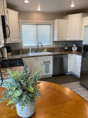 Enjoy cooking in this kitchen with white cabinetry, a dishwasher, and granite countertop.