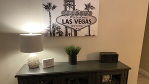 Une console en bois foncé, surmontée d’une lampe allumée, d’une petite plante en pot et de quelques objets décoratifs.