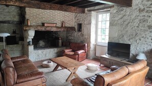 A rustic living room with leather sofas, a wooden coffee table, a fireplace, and a television. - Demeure de Charme 10 Personnes Avec Piscine (Sainte-Colombe-en-Bruilhois)
