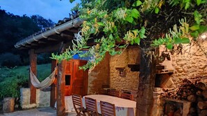 A rustic outdoor dining area with a stone wall, wooden table, and chairs. - Demeure de Charme 10 Personnes Avec Piscine (Sainte-Colombe-en-Bruilhois)