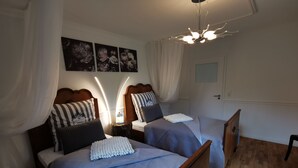 A bedroom with two beds, each with a wooden headboard, a bedside table with a lamp, and a wall-mounted artwork above the beds. - Apartment Tilia (Ivenack)
