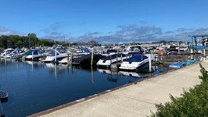 A marina with multiple boats docked, a concrete walkway, and a clear blue sky. - Perfect Location for your Beach/Lake MI stay!  You'll Love This Beautiful Home! (New Buffalo)