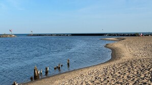 A sandy beach with calm water, wooden posts, and a distant jetty. - Perfect Location for your Beach/Lake MI stay!  You'll Love This Beautiful Home! (New Buffalo)