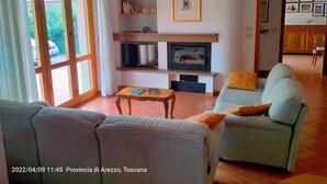 Una sala de estar con un sofá, una televisión y una estantería.