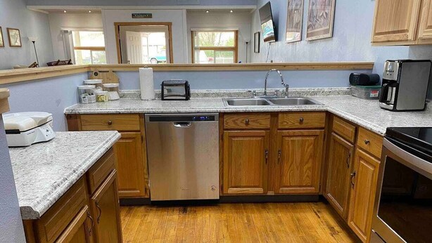 Eine moderne Küche mit Holzschränken, einem Edelstahl-Geschirrspüler, einem eingebauten Backofen und einer Arbeitsplatte aus Granit.