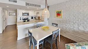 Una cocina moderna con armarios blancos, una isla central y una lámpara colgante.