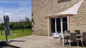 A stone building with a patio area featuring outdoor seating and a covered table. - House in the countryside near Omaha Beach! Pets allowed (Mandeville-en-Bessin)