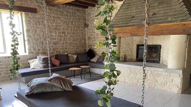 A cozy living room with a stone wall, a fireplace, a sofa, and a hanging plant. - House in the countryside near Omaha Beach! Pets allowed (Mandeville-en-Bessin)
