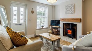 A living room with a fireplace, a television, and a large window with decorative glass panes. - 2 bedroom accommodation in Holt (Holt)