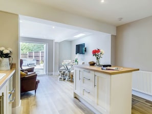 A modern kitchen with white cabinetry, a dining area with a table and chairs, and a view into the backyard. - 2 bedroom accommodation in Holt (Holt)