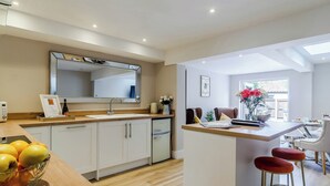 A modern kitchen with a wooden countertop, a sink, and a mirror above it. There is a dining area with a table and chairs. - 2 bedroom accommodation in Holt (Holt)