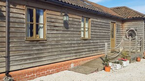 A wooden building with a tiled roof, a brick foundation, and a small porch area with potted plants.