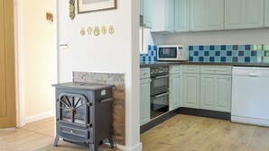 A kitchen with a wood-burning stove, a microwave, and a dishwasher.