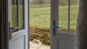 A door leading to a grassy outdoor area with a stone wall and steps.